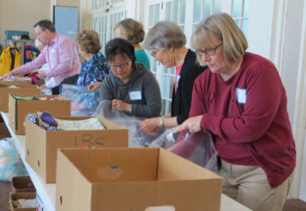 An assembly line packs Safe Motherhood Kits from boxes of supplies.