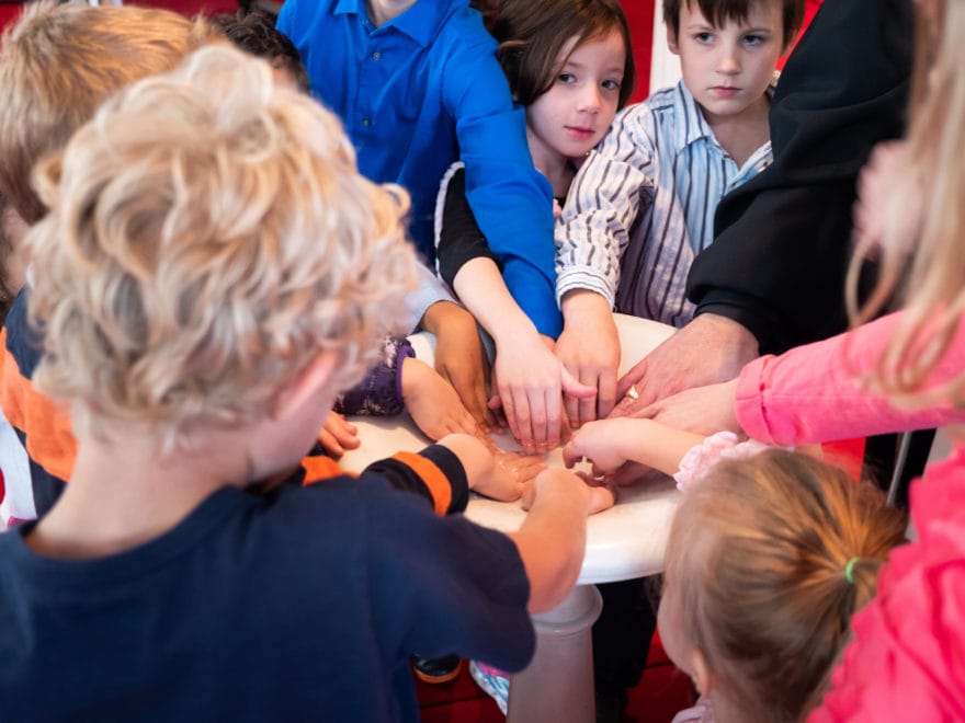 A group of children place their hands in the baptismal font.