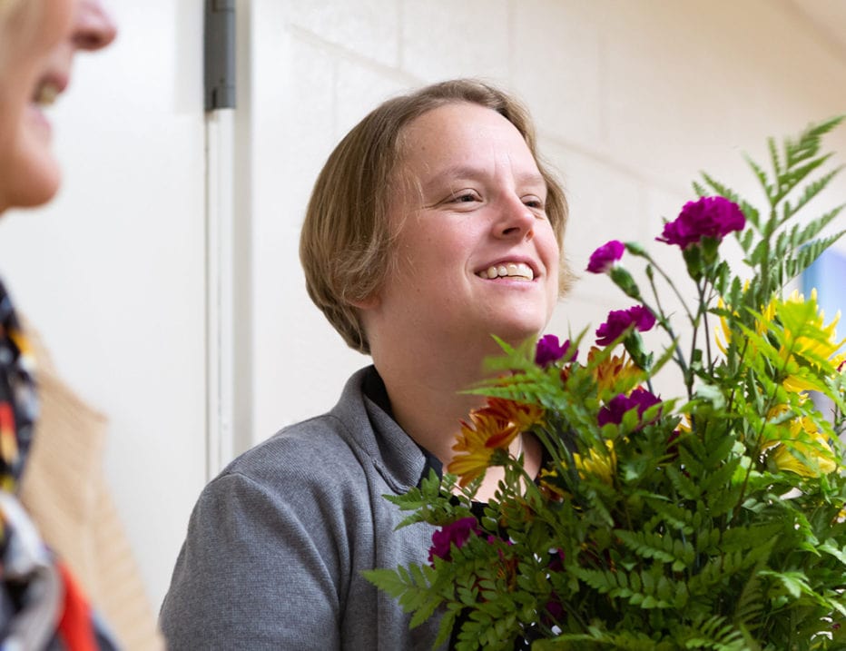A woman delivers flowers to a nursing home.