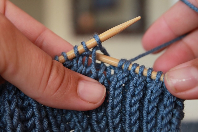 hands holding blue knitting work