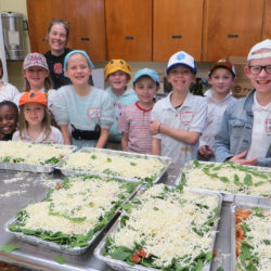 Elementary school youth smile with the casseroles they assembled for the shelter