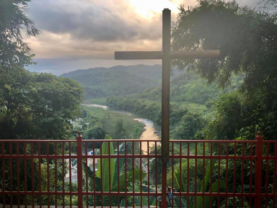 A cross overlooks a valley and river in Puerto Rico