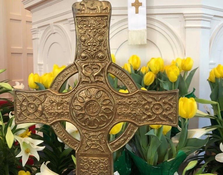The cross and Easter lilies and tulips sit in front of the pulpit