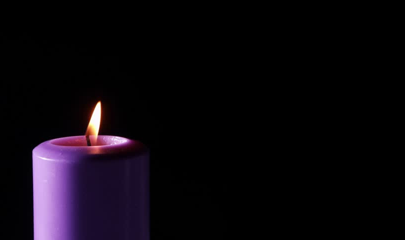 A single purple candle is lit against a black background