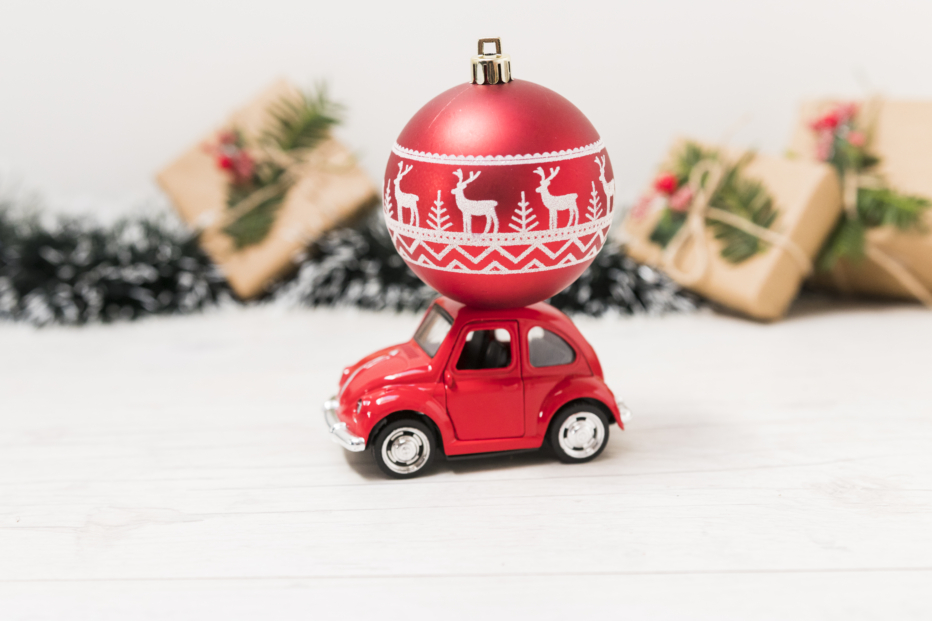 a red toy car has a red Christmas ornament on top