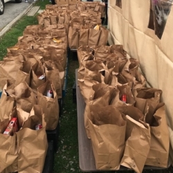 Brown paper bags filled with food are lined up awaiting distribution at the Grace AME food drive.