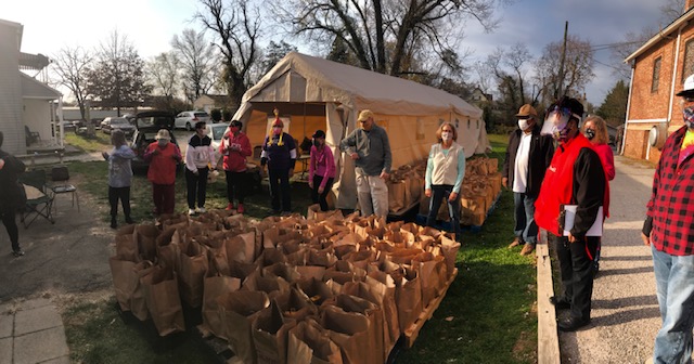 Volunteers stand around paper bags of food ready to distribute at Grace AME's Thanksgiving food drive.