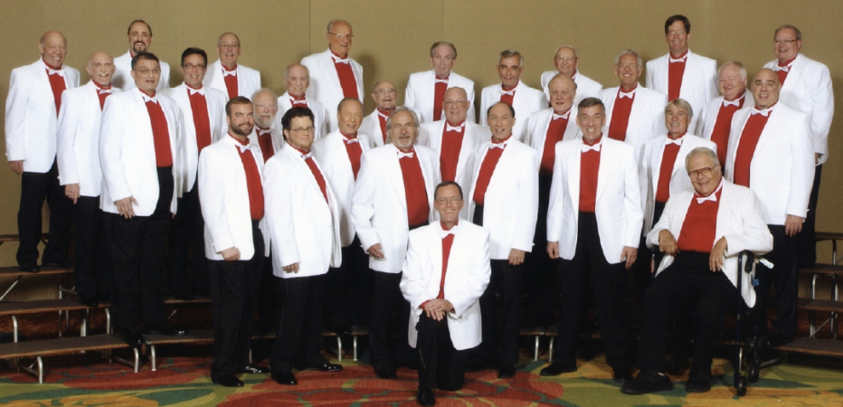 The 29 members of the Heart of Maryland Barbershop Chorus are seen wearing white jackets and red shirts.