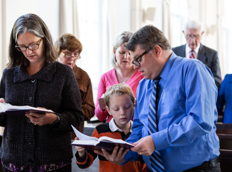 A couple with a young son sing a hymn together during worship.