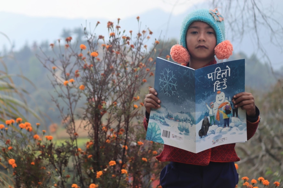 A young girl holds a book published by Santi School in Nepal