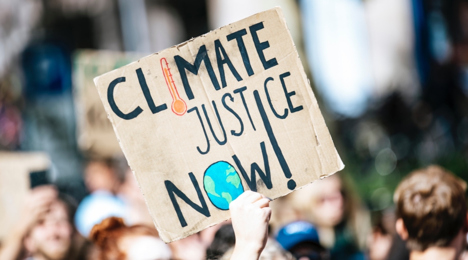 Protest sign stating "Climate Justice Now"
